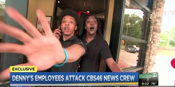 Employee confronts camera at restaurant entrance.