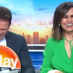 Two TV hosts laughing on morning show set.