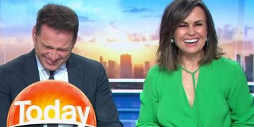 Two TV hosts laughing on morning show set.