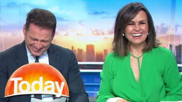 Two TV hosts laughing on morning show set.
