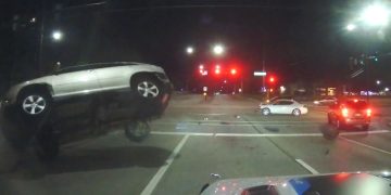 Car collision at night intersection, vehicle flipping over.