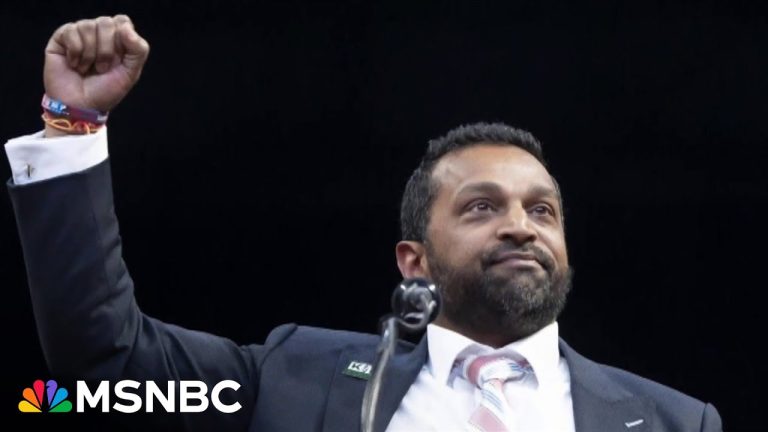 Person raising fist, wearing suit on stage.