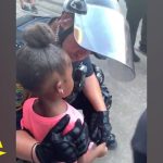 Police officer comforting young girl at protest.