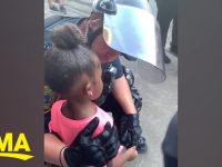 Police officer comforting young girl at protest.