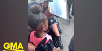 Police officer comforting young girl at protest.