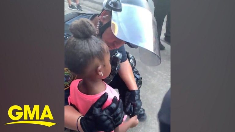 Police officer comforting young girl at protest.