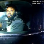 Driver in a car during nighttime police stop.