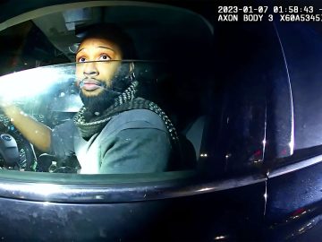 Driver in a car during nighttime police stop.