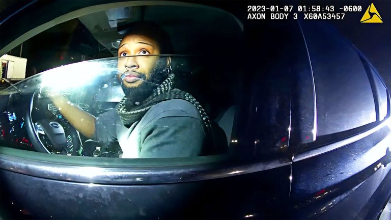 Driver in a car during nighttime police stop.