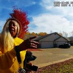 Person in yellow sweater gesturing on suburban street.