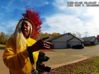 Person in yellow sweater gesturing on suburban street.