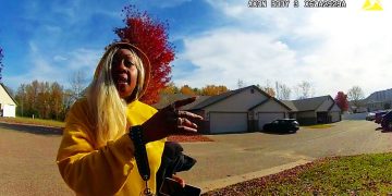 Person in yellow sweater gesturing on suburban street.