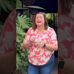 Woman laughing outdoors near leafy plants