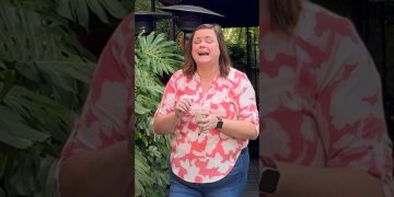 Woman laughing outdoors near leafy plants