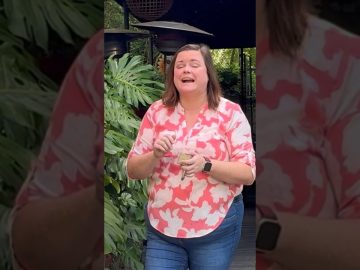 Woman laughing outdoors near leafy plants