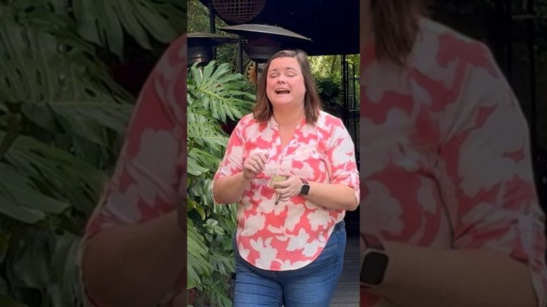 Woman laughing outdoors near leafy plants
