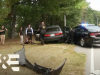 Police at car crash scene with suspect detained.