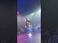 Person dancing onstage with audience behind.