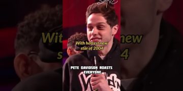 Comedian on stage with microphone, humorous roasting.
