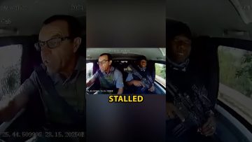Car interior with driver and armed passenger.