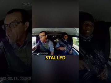 Car interior with driver and armed passenger.