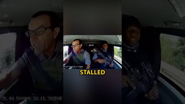 Car interior with driver and armed passenger.