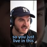 Person wearing headphones and a baseball cap speaking.
