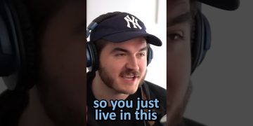 Person wearing headphones and a baseball cap speaking.