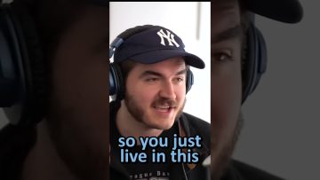 Person wearing headphones and a baseball cap speaking.