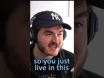 Person wearing headphones and a baseball cap speaking.