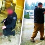 Police officer kneeling with gun inside garage.