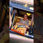 Woman surprised holding takeaway pizza box in drive-thru.