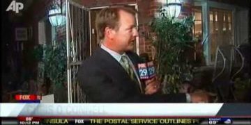 Reporter conducting outdoor interview at night.