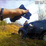 Person points gun at SUV in rural area.