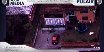 Aerial view of house, car, and garden scene.