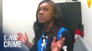 Person in office setting, hands raised, looking up.