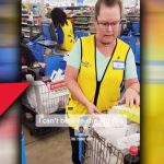 Store employee at checkout counter with cart.