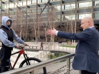 Man gestures at cyclist in urban park setting.