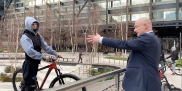 Man gestures at cyclist in urban park setting.