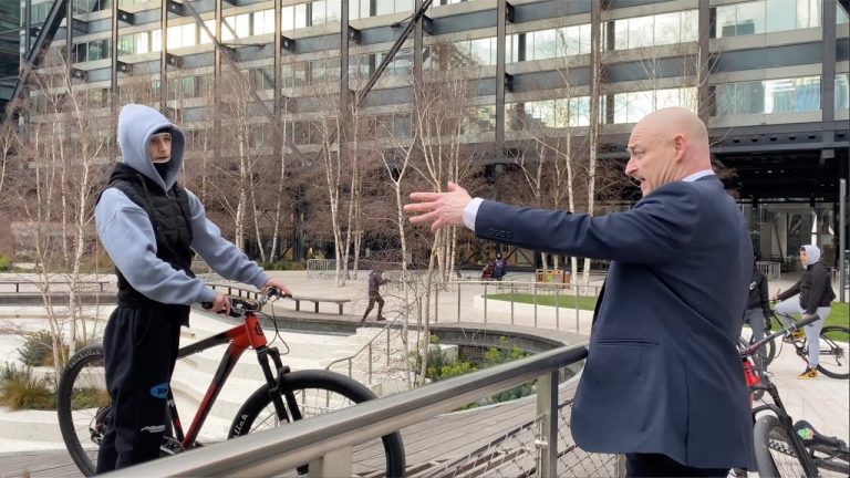 Man gestures at cyclist in urban park setting.
