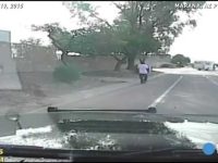 Dashcam captures person walking on road, trees nearby.