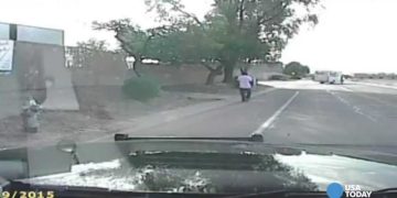 Dashcam captures person walking on road, trees nearby.