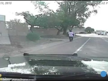Dashcam captures person walking on road, trees nearby.