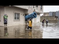 People wading through flooded street carrying items.
