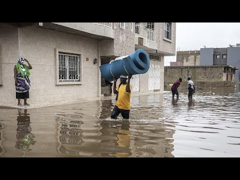 People wading through flooded street carrying items.