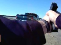 Person aiming gun at truck on road.
