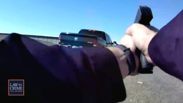 Person aiming gun at truck on road.