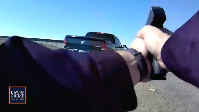 Person aiming gun at truck on road.