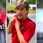 Person in red shirt looking surprised outdoors.
