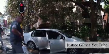 Police arrest beside silver car at traffic light.